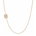 A delicate gold chain necklace featuring a small flower-shaped pendant paved with clear stones, displayed against a solid white background.