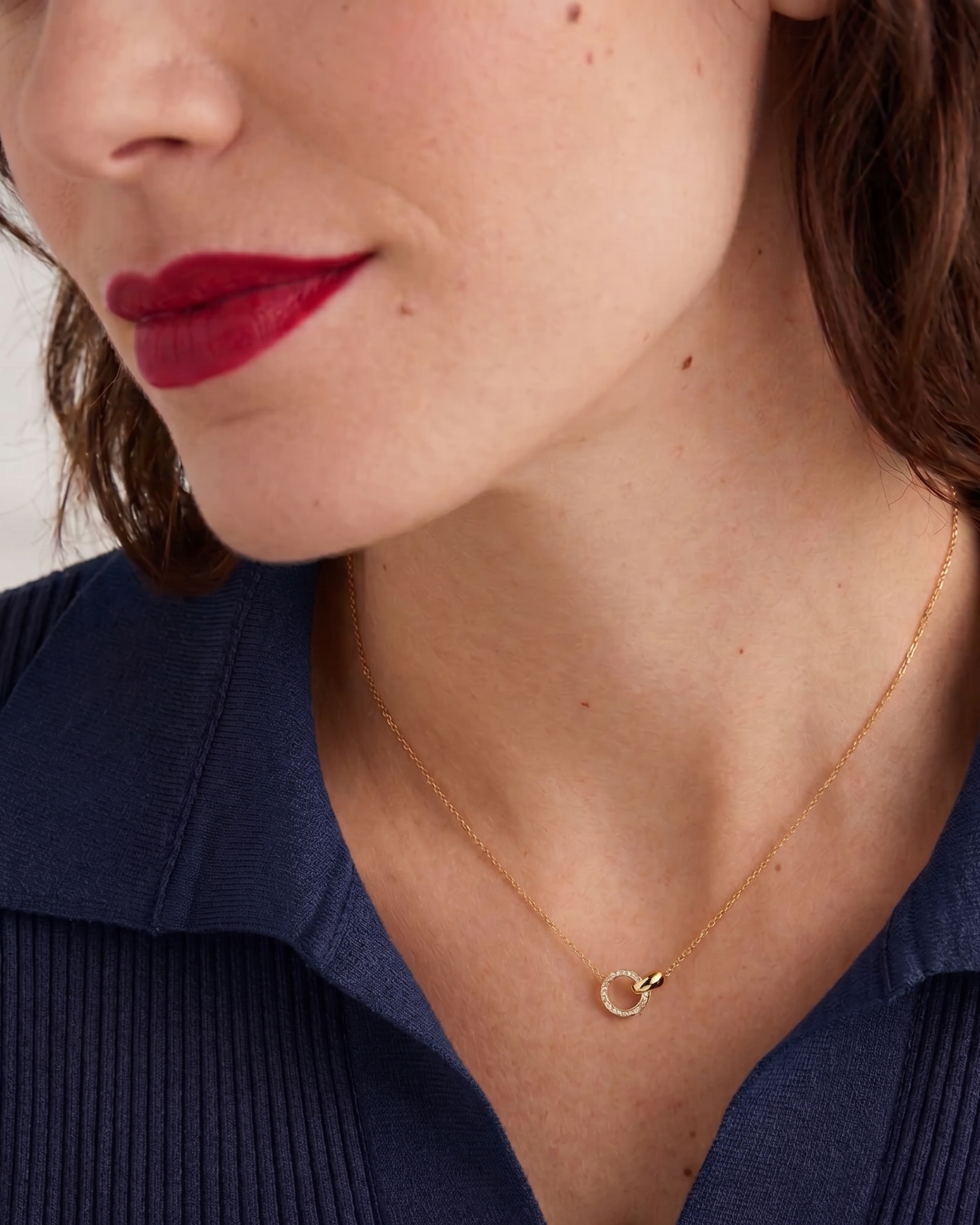 Close-up of a woman wearing a gold necklace with a small pendant.