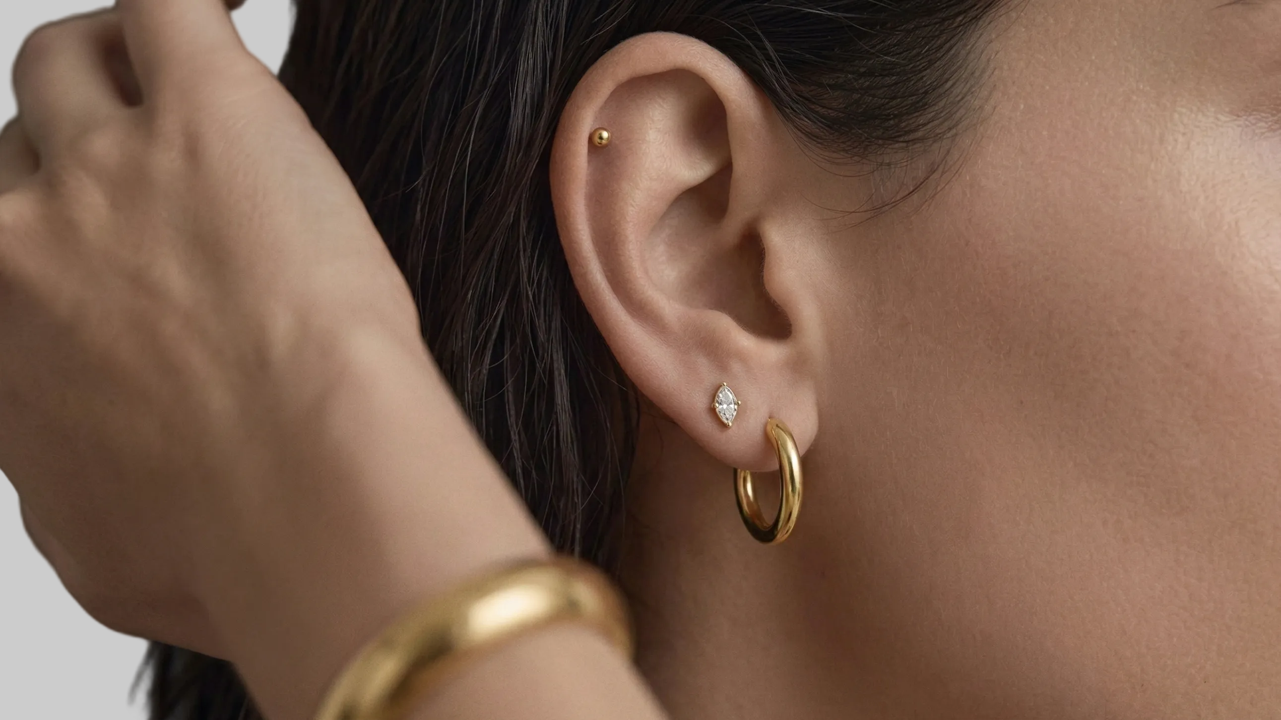 Close-up of a person wearing gold hoop earrings with a blurred background