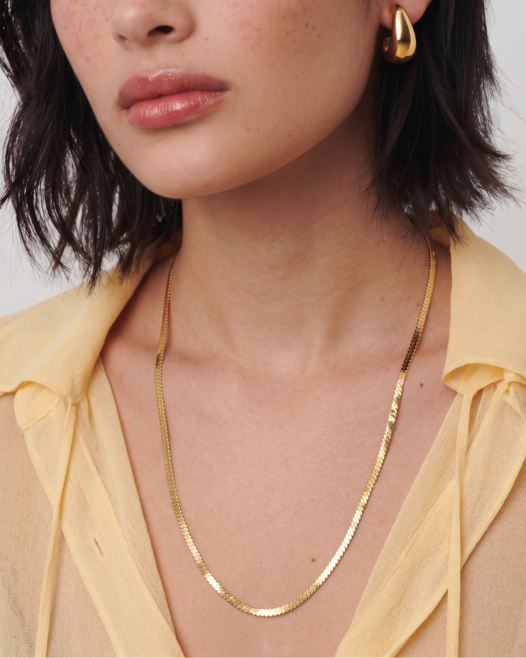 Woman wearing gold jewelry against a plain background