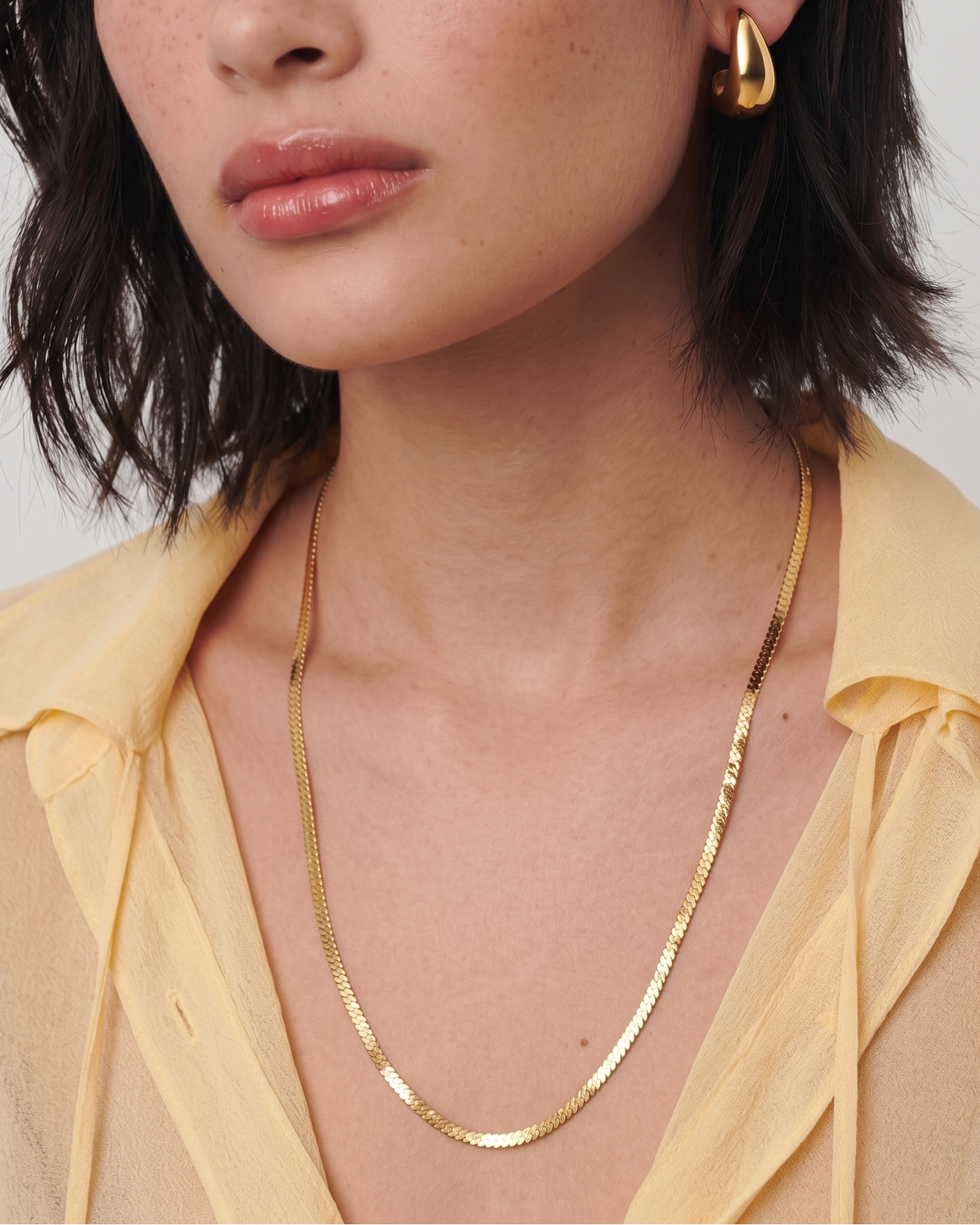 Woman wearing gold jewelry against a plain background