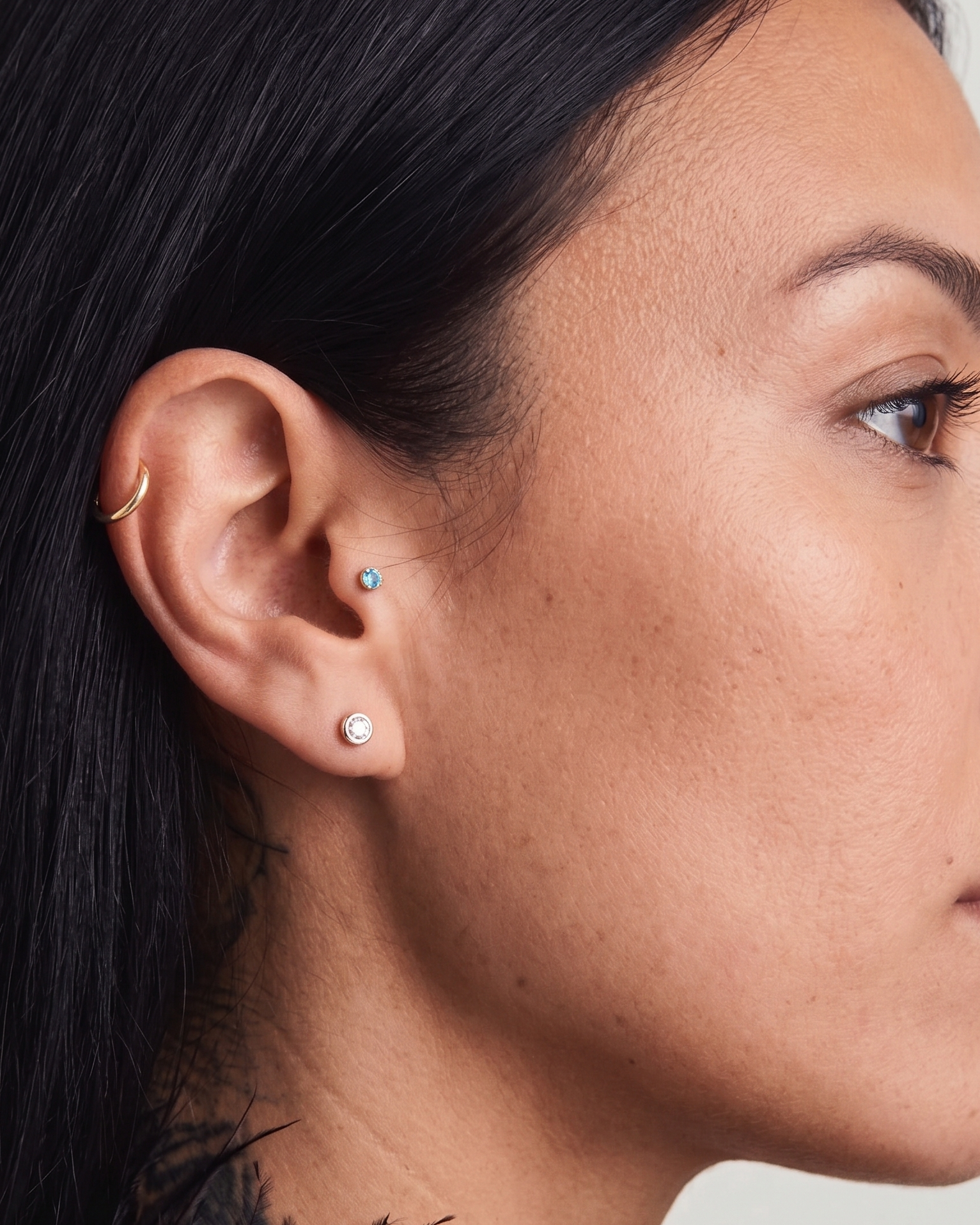 Close-up of a woman's ear with earrings against a neutral background