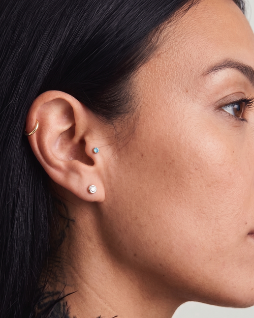 Close-up of a woman's ear with earrings against a neutral background
